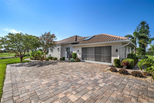 view of front of property featuring a garage, decorative driveway, a tile roof, and stucco siding