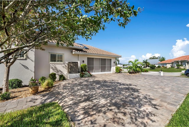 mediterranean / spanish house featuring a garage, a tiled roof, decorative driveway, and stucco siding