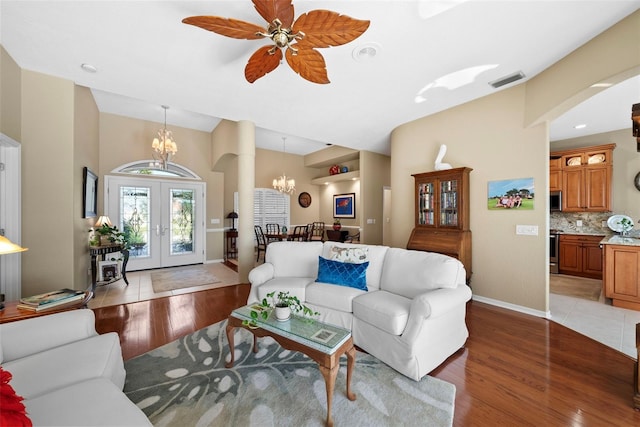 living area featuring arched walkways, visible vents, baseboards, light wood-style floors, and french doors