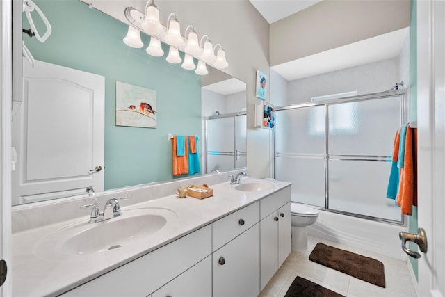 full bath with double vanity, toilet, a sink, and tile patterned floors