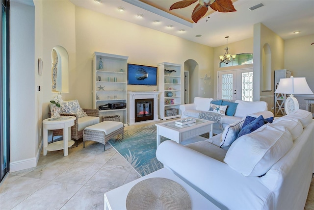 living room featuring visible vents, a high ceiling, arched walkways, and a glass covered fireplace