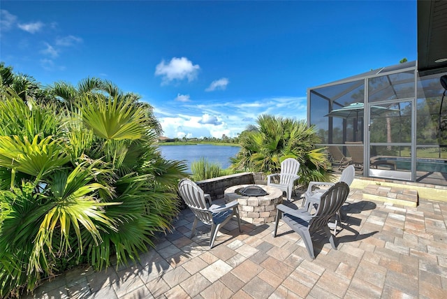 view of patio / terrace featuring a fire pit, glass enclosure, and a water view