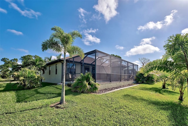 back of house with a lawn, a lanai, and stucco siding