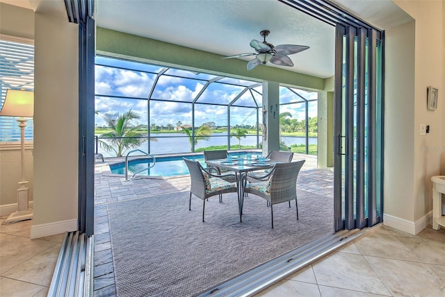 sunroom featuring a ceiling fan and a water view