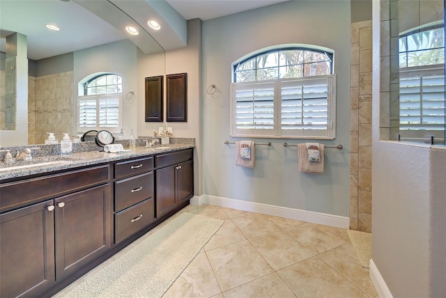 full bath with double vanity, baseboards, and a sink