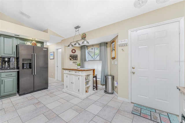 kitchen with stainless steel fridge with ice dispenser, green cabinetry, a textured ceiling, and light tile patterned floors