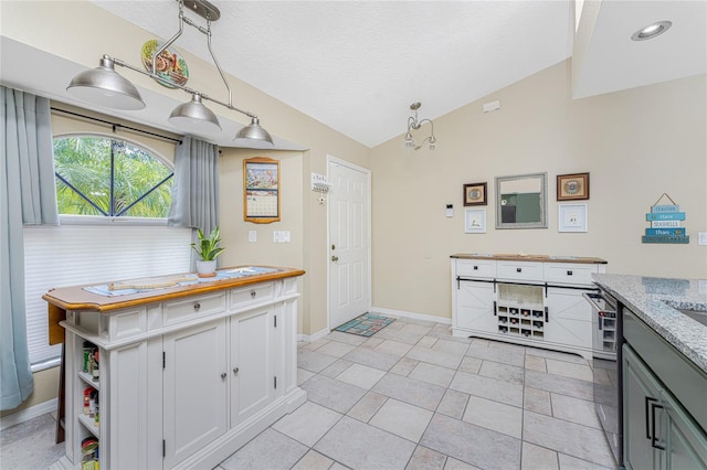 kitchen featuring light tile patterned flooring, white cabinetry, lofted ceiling, and dishwasher