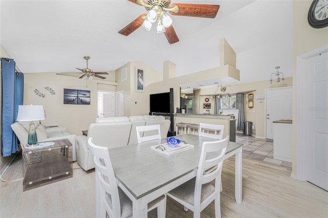 dining room featuring ceiling fan, light wood-type flooring, and vaulted ceiling