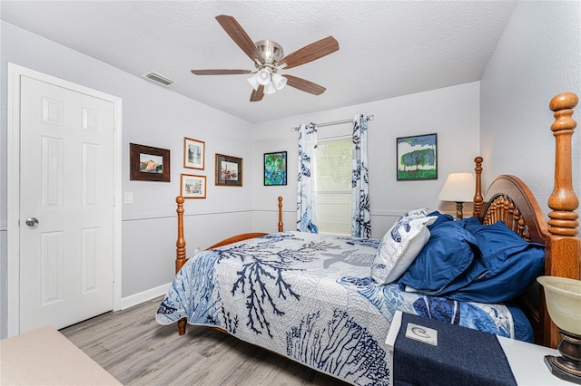 bedroom featuring ceiling fan, a textured ceiling, and light hardwood / wood-style flooring