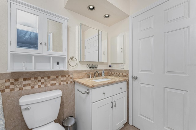 bathroom with tile walls, vanity, and toilet