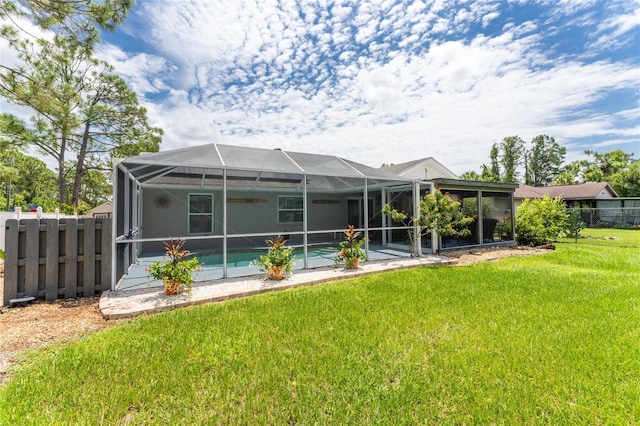 rear view of house featuring glass enclosure and a yard