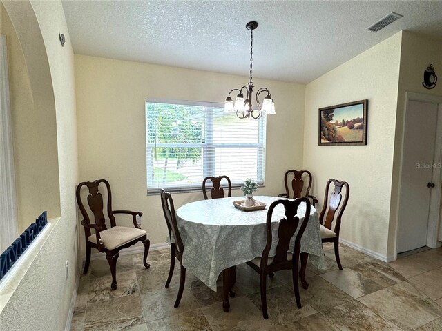 dining area featuring tile patterned flooring, a textured ceiling, a notable chandelier, and lofted ceiling