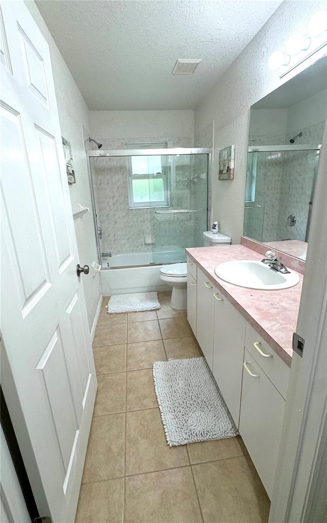 full bathroom with tile patterned floors, vanity, combined bath / shower with glass door, and toilet