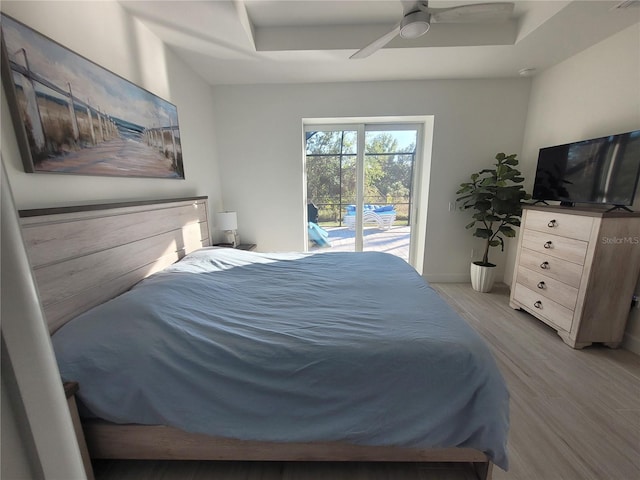 bedroom featuring ceiling fan, a raised ceiling, access to outside, and light hardwood / wood-style flooring