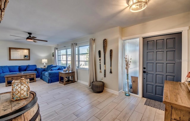 foyer entrance featuring light wood finished floors, ceiling fan, and baseboards