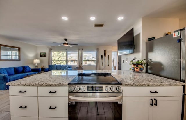 kitchen with white cabinets, light hardwood / wood-style floors, light stone countertops, and stainless steel appliances