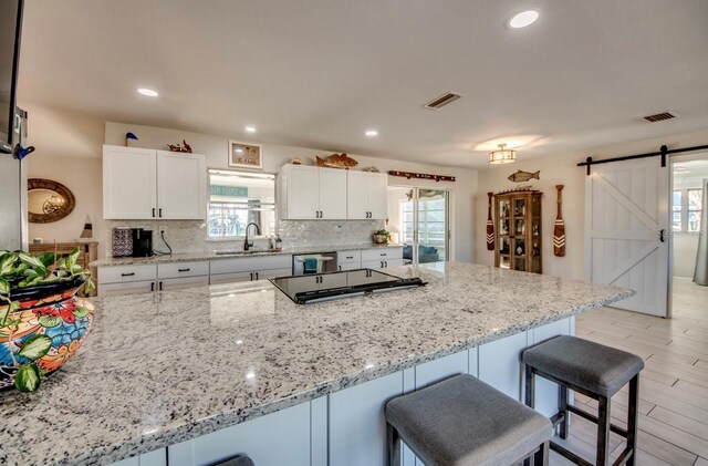 kitchen featuring a barn door, white cabinetry, sink, and light hardwood / wood-style flooring