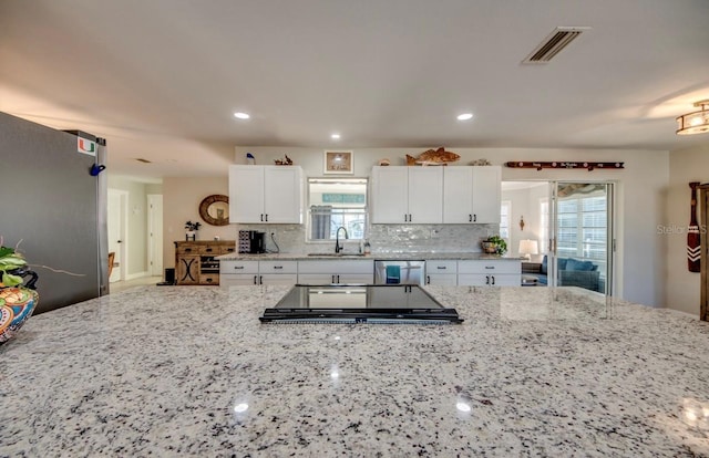 kitchen with white cabinets, stainless steel appliances, and light stone counters