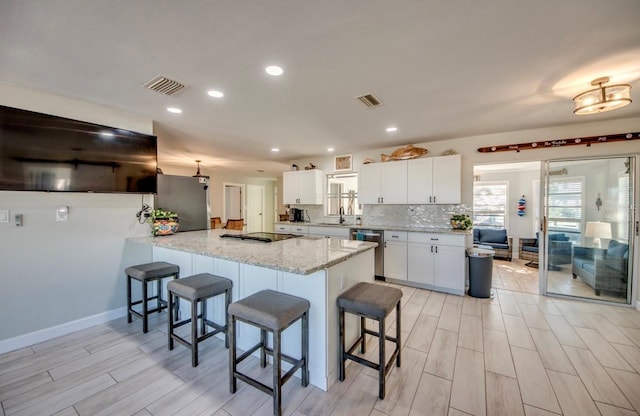 kitchen with visible vents, white cabinets, a kitchen breakfast bar, a peninsula, and stainless steel appliances