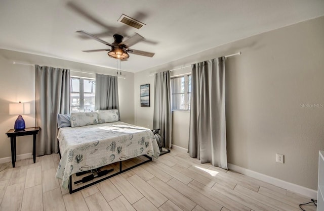 bedroom featuring wood tiled floor, multiple windows, visible vents, and baseboards