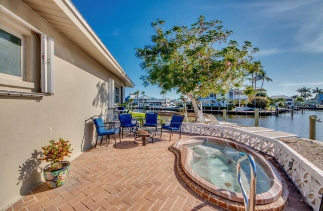 view of patio with an in ground hot tub and a water view