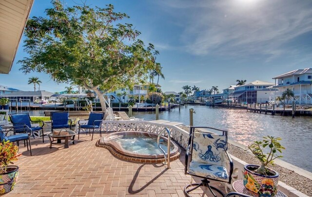 view of dock featuring an in ground hot tub, a water view, and a patio