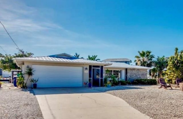 view of front of property with a garage, driveway, and metal roof