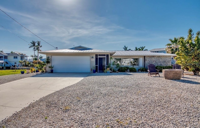 ranch-style house with metal roof, a garage, driveway, stucco siding, and a standing seam roof