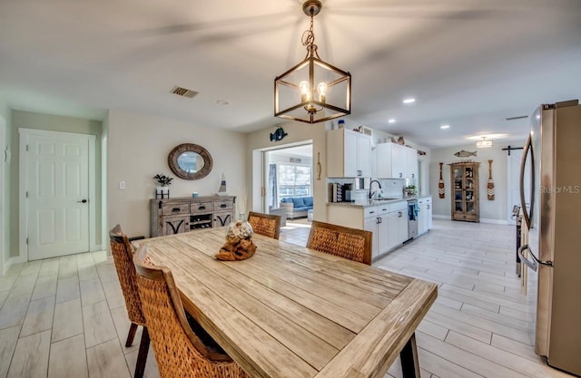 dining room featuring sink, light hardwood / wood-style floors, and an inviting chandelier