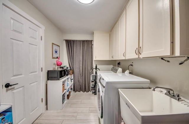 laundry room featuring cabinets, separate washer and dryer, sink, and light hardwood / wood-style flooring