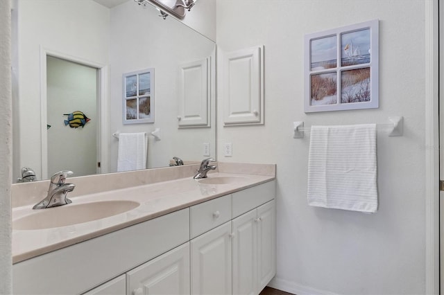 full bathroom featuring a sink, baseboards, and double vanity