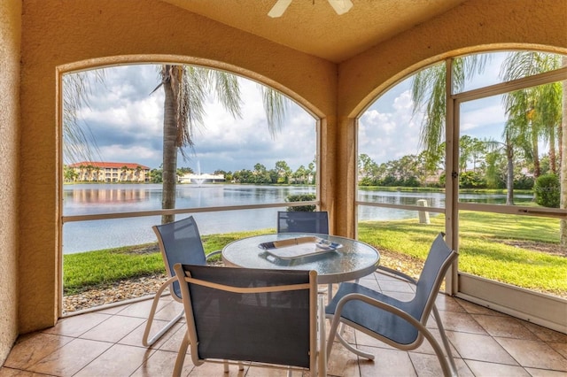 sunroom featuring ceiling fan, a water view, and lofted ceiling