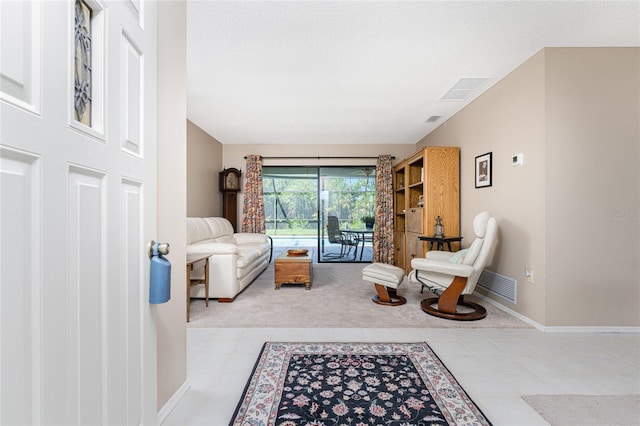 living room with baseboards, a textured ceiling, visible vents, and tile patterned floors