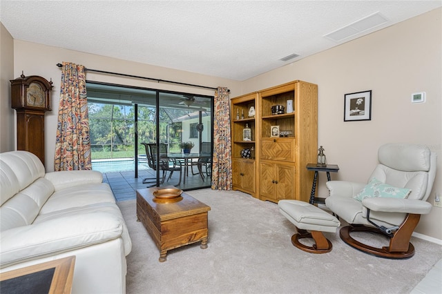 living room with carpet floors, visible vents, and a textured ceiling