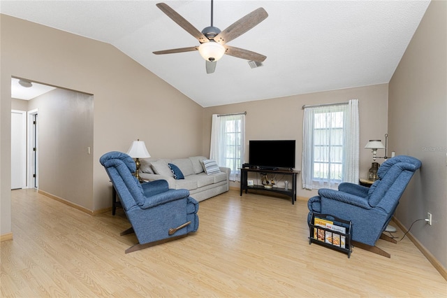 living room with light wood-style flooring, visible vents, vaulted ceiling, and a wealth of natural light