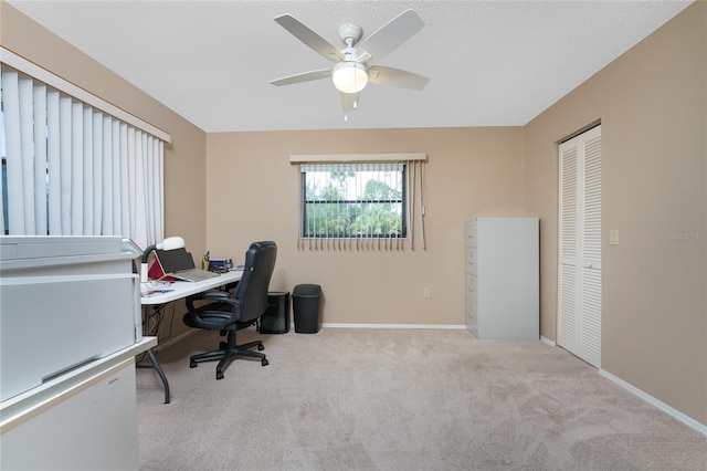 carpeted home office with ceiling fan and baseboards