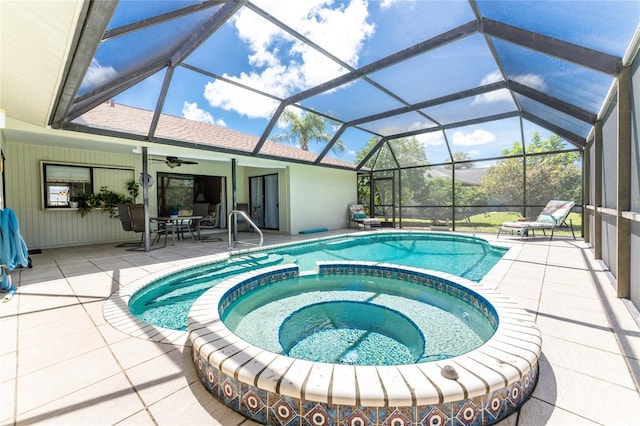 view of pool featuring a ceiling fan, glass enclosure, a pool with connected hot tub, and a patio area