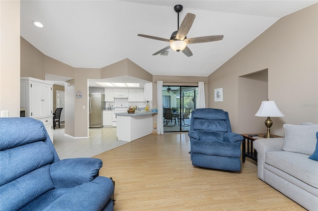 living area with visible vents, vaulted ceiling, ceiling fan, light wood-type flooring, and baseboards