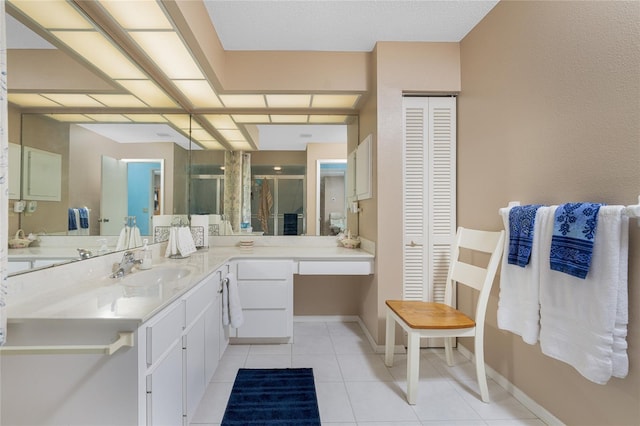 full bathroom featuring tile patterned flooring, vanity, baseboards, a closet, and a stall shower