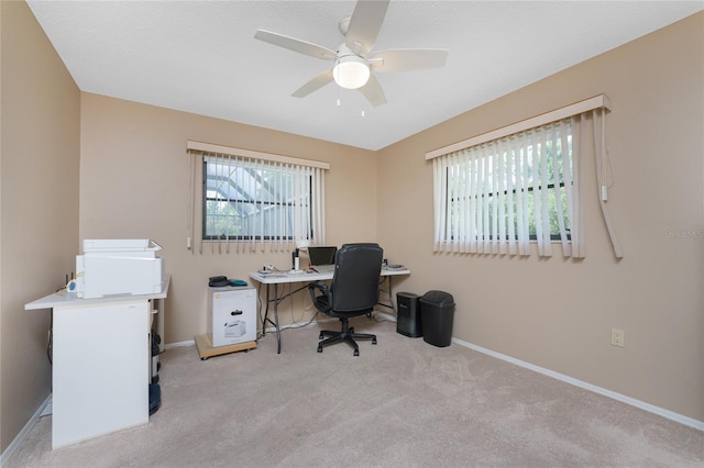 carpeted office with ceiling fan and baseboards