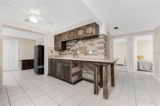 kitchen featuring tasteful backsplash, sink, black fridge, ceiling fan, and a breakfast bar