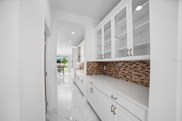 kitchen with backsplash, white cabinetry, and ornamental molding