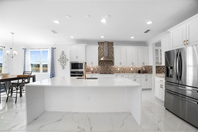 kitchen with wall chimney exhaust hood, white cabinetry, stainless steel appliances, and a large island