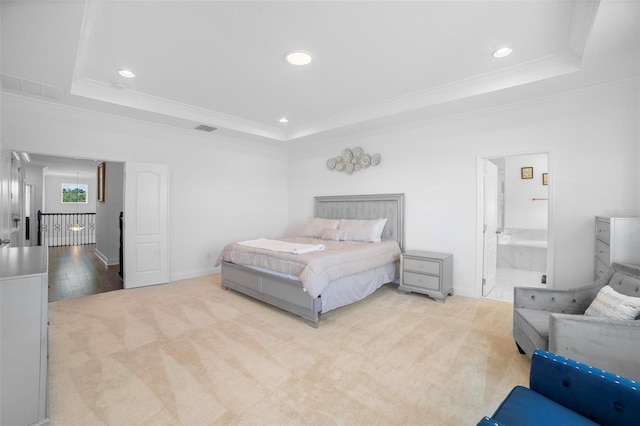 bedroom with a tray ceiling, ensuite bathroom, crown molding, and light hardwood / wood-style flooring