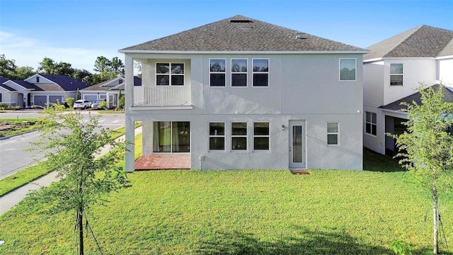 back of property featuring a balcony and a lawn