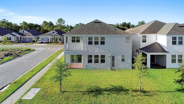 rear view of property with a balcony and a lawn