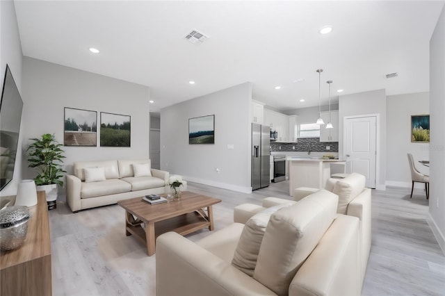 living room featuring sink and light hardwood / wood-style floors