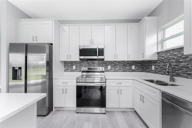 kitchen with appliances with stainless steel finishes, sink, white cabinets, and backsplash