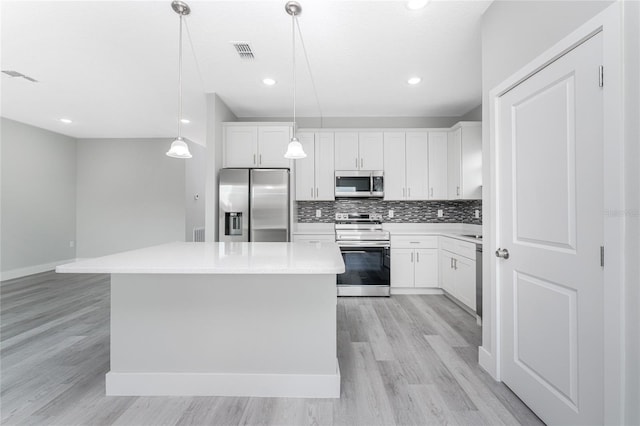 kitchen featuring stainless steel appliances, decorative light fixtures, decorative backsplash, a kitchen island, and white cabinetry