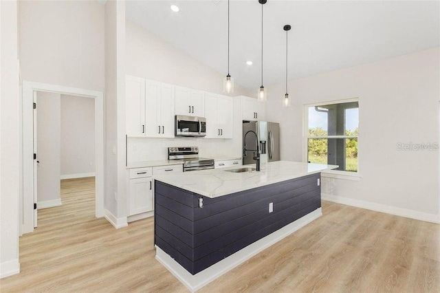 kitchen featuring light wood-type flooring, stainless steel appliances, light stone countertops, and white cabinetry